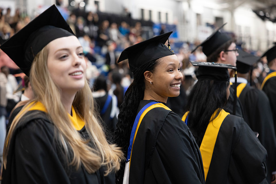 Graduates in caps and gowns stand in line as they wait to be seated at the Commencement ceremony